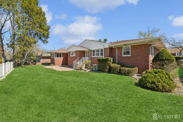 back of house featuring central AC unit, a patio area, a yard, brick siding, and fence