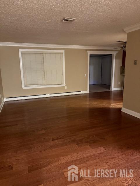 unfurnished room featuring a textured ceiling, crown molding, and dark wood-type flooring