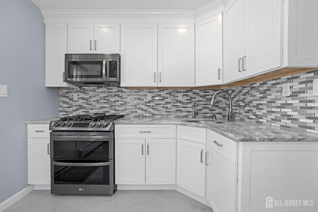 kitchen featuring tasteful backsplash, white cabinetry, appliances with stainless steel finishes, and sink