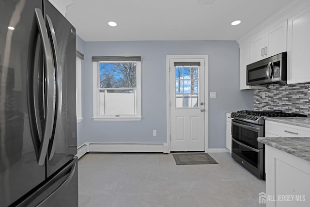 kitchen featuring appliances with stainless steel finishes, white cabinets, light stone countertops, decorative backsplash, and a baseboard heating unit