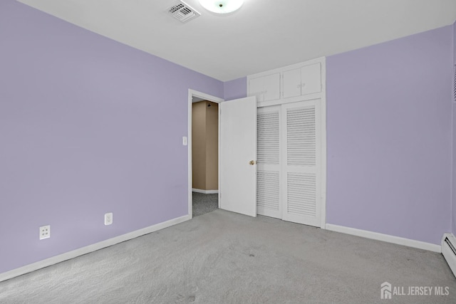 unfurnished bedroom with light carpet, a closet, and baseboard heating