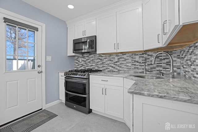 kitchen featuring white cabinetry, sink, light stone countertops, and appliances with stainless steel finishes