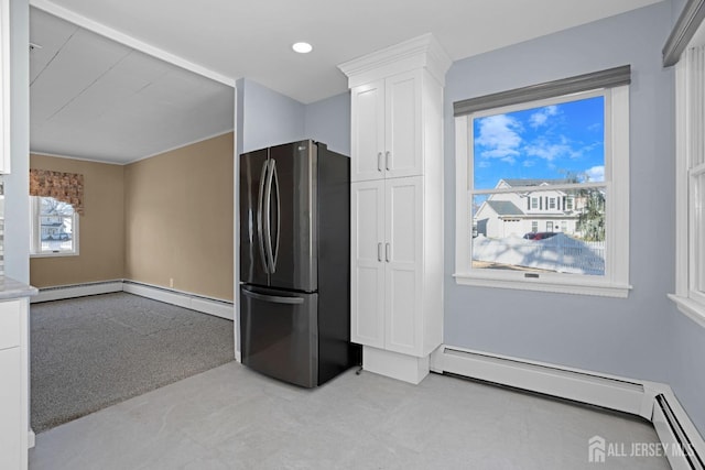 kitchen featuring stainless steel refrigerator, white cabinetry, a baseboard radiator, and light carpet