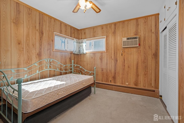 carpeted bedroom with a wall mounted air conditioner, wood walls, a baseboard radiator, ceiling fan, and a closet