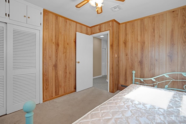 carpeted bedroom with ceiling fan, a baseboard radiator, a closet, and wood walls