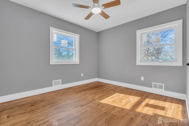 empty room with ceiling fan, hardwood / wood-style floors, and a healthy amount of sunlight