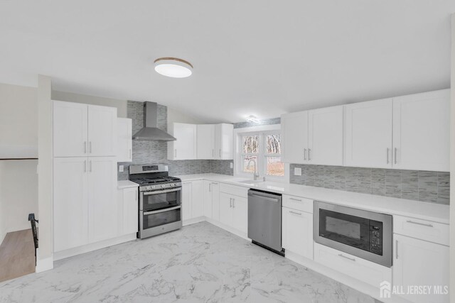 kitchen featuring tasteful backsplash, white cabinets, wall chimney exhaust hood, and stainless steel appliances