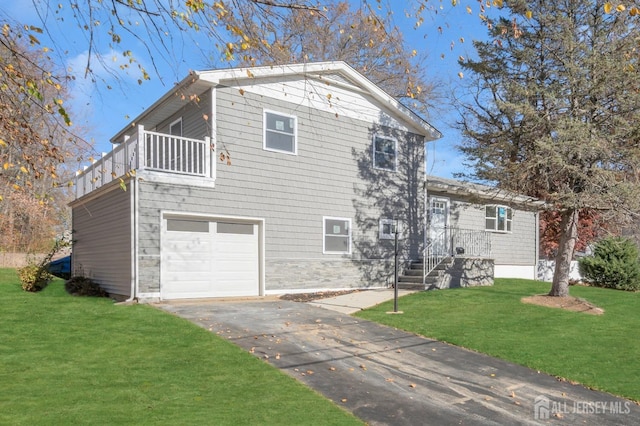 view of front of home featuring a garage, a balcony, and a front lawn