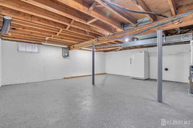 basement with white refrigerator, electric panel, and water heater