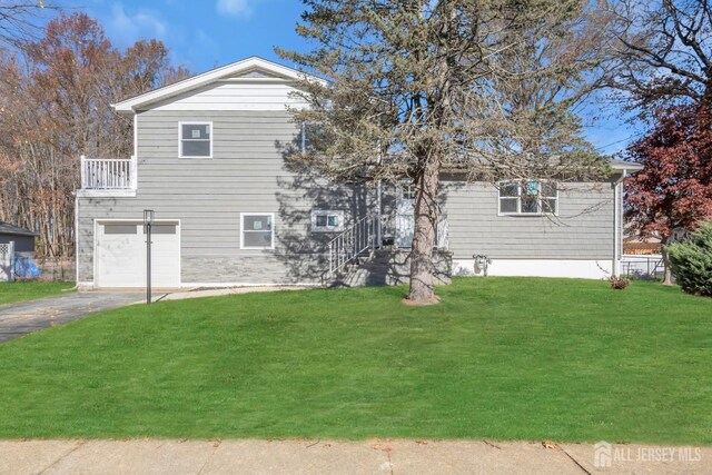 view of front facade featuring a balcony, a front lawn, and a garage