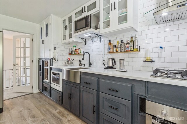 1 Hollywood Dr, Woodbridge Proper, NJ 07095 - kitchen featuring appliances with stainless steel finishes, light countertops, white cabinets, light wood-type flooring, and a sink