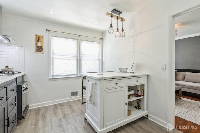 1 Hollywood Dr, Woodbridge Proper, NJ 07095 - kitchen with wall oven, light wood-style floors, exhaust hood, light countertops, and decorative light fixtures