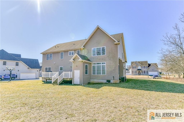 rear view of property with a lawn, a garage, and central AC