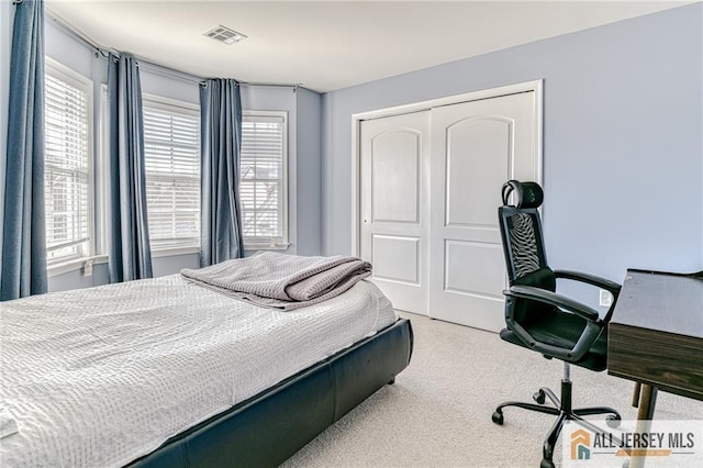 carpeted bedroom featuring visible vents and a closet