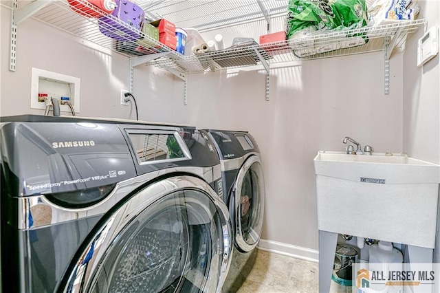 laundry area featuring washer and dryer, baseboards, laundry area, and a sink