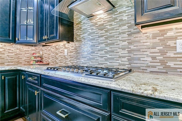 kitchen featuring light stone countertops, extractor fan, stainless steel gas stovetop, blue cabinets, and tasteful backsplash