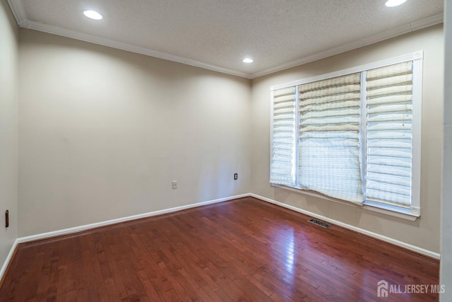 spare room featuring baseboards, a textured ceiling, ornamental molding, and wood finished floors