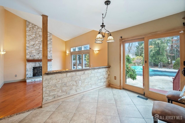 kitchen with light tile patterned floors, a fireplace, a wealth of natural light, and decorative light fixtures