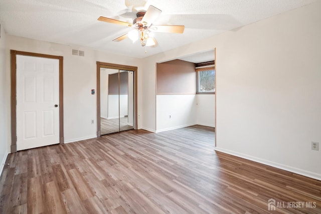 spare room featuring a ceiling fan, visible vents, light wood-style flooring, and baseboards