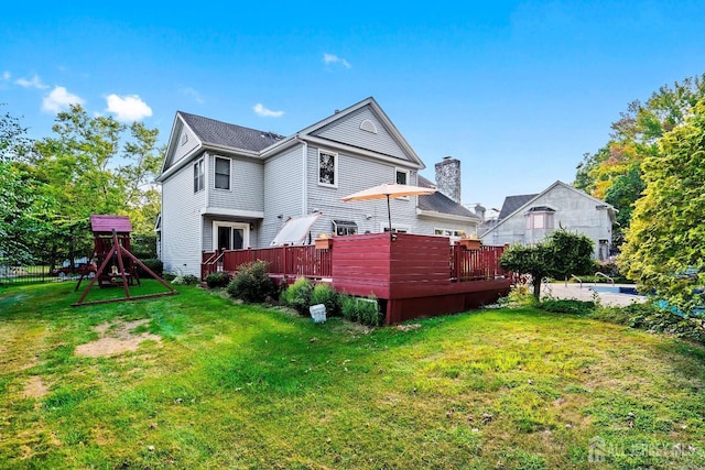 back of property with a yard, a playground, and a wooden deck