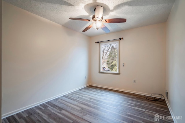 unfurnished room featuring baseboards, dark wood finished floors, and a textured ceiling