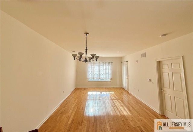 unfurnished dining area with a notable chandelier, visible vents, light wood-style flooring, and baseboards