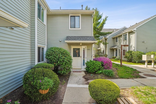 doorway to property with a shingled roof