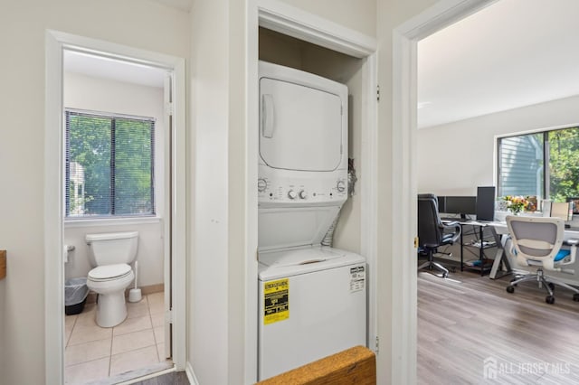 laundry area featuring stacked washer / drying machine, a desk, and wood finished floors
