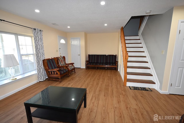 living area with light wood finished floors, recessed lighting, a textured ceiling, and stairs