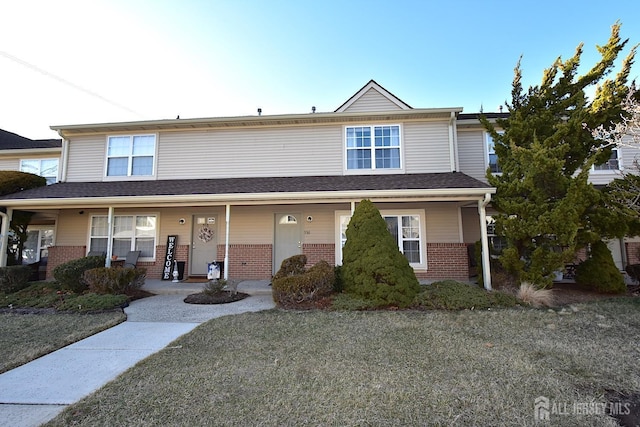 multi unit property with brick siding, covered porch, and a shingled roof