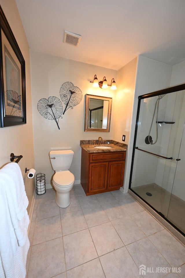 bathroom with tile patterned floors, toilet, a shower with door, and vanity