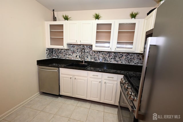 kitchen featuring tasteful backsplash, white cabinetry, sink, light tile patterned floors, and stainless steel appliances