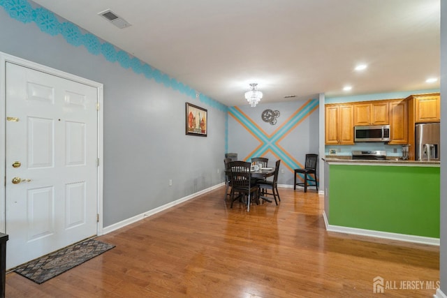 kitchen featuring an inviting chandelier, light hardwood / wood-style flooring, and appliances with stainless steel finishes