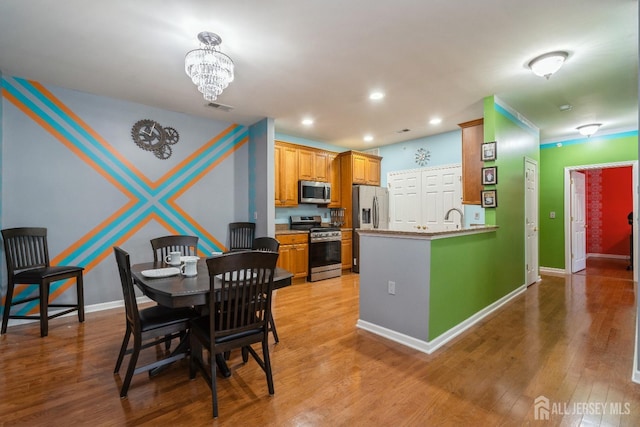 dining area featuring sink, a notable chandelier, and light hardwood / wood-style floors