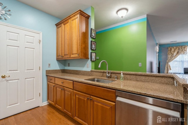 kitchen featuring stone counters, sink, stainless steel dishwasher, and light hardwood / wood-style flooring