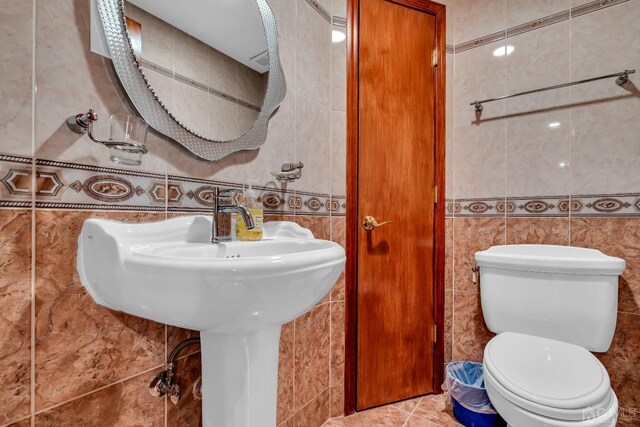 bathroom featuring tile patterned flooring, tile walls, and toilet