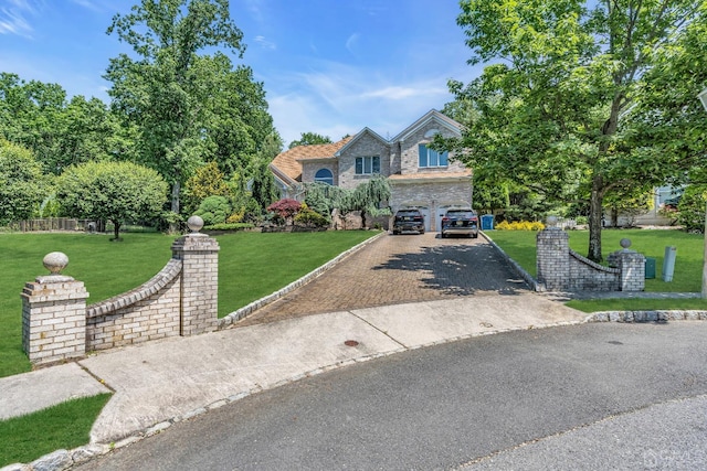 view of front of home featuring an attached garage, driveway, stone siding, and a front yard