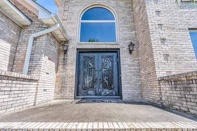 view of exterior entry featuring fence and brick siding