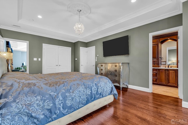 bedroom with visible vents, baseboards, wood finished floors, an inviting chandelier, and crown molding