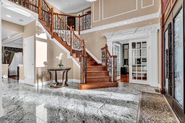 foyer with french doors, a high ceiling, and ornamental molding