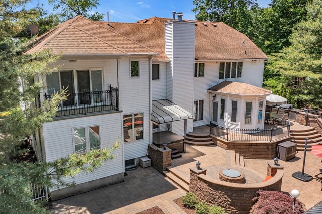 rear view of property with a jacuzzi, a patio, and an outdoor fire pit