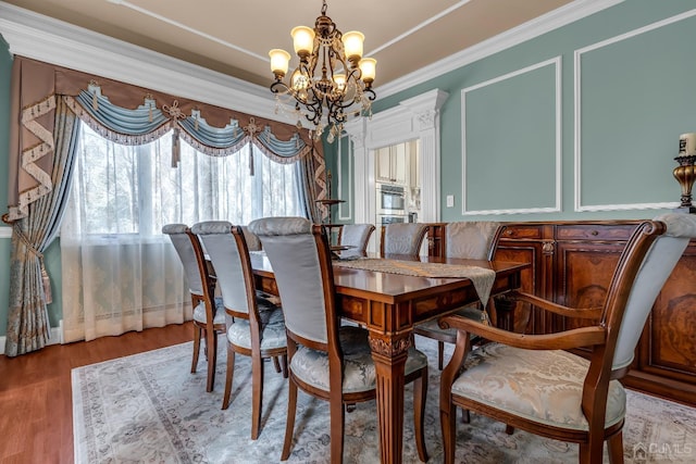 dining area featuring ornamental molding, wood finished floors, and a notable chandelier