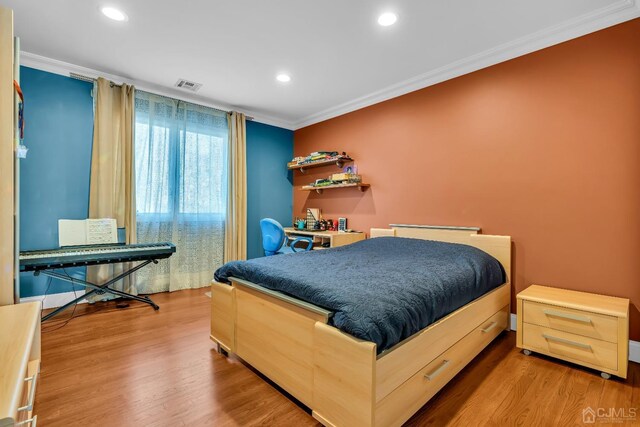 bedroom with ornamental molding and light wood-type flooring