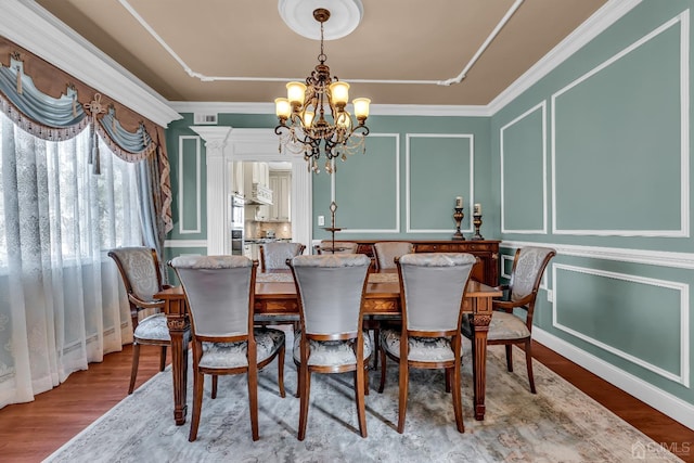 dining room with hardwood / wood-style floors, crown molding, and a chandelier