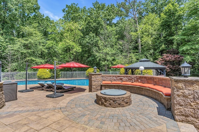 view of swimming pool featuring a fire pit, a gazebo, a patio area, and fence