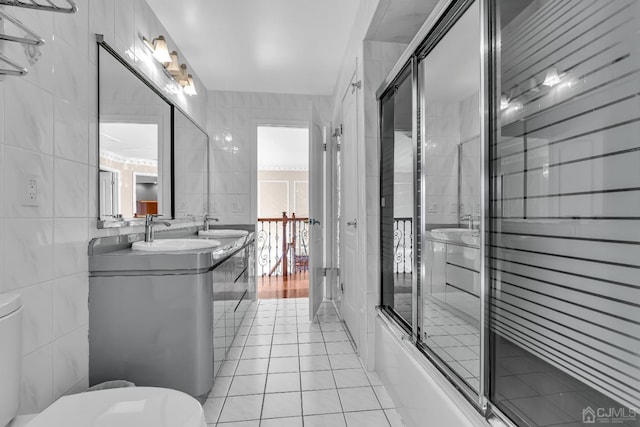 full bath featuring double vanity, tile walls, toilet, tile patterned floors, and a sink