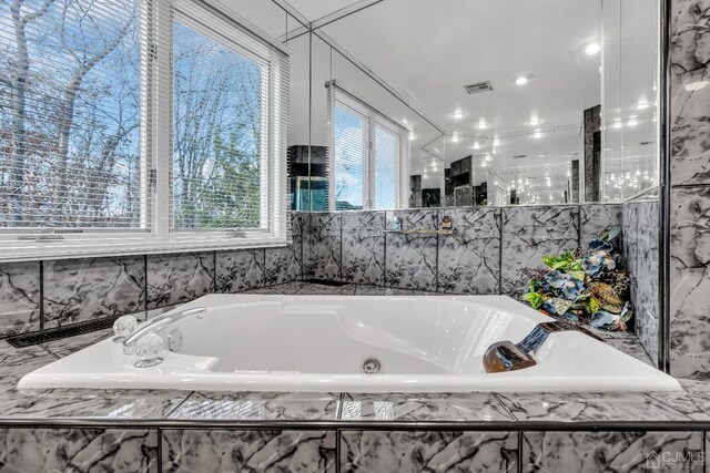 bathroom featuring tiled bath and a healthy amount of sunlight