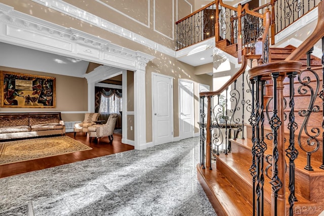 interior space with wood finished floors, a towering ceiling, baseboards, and stairs