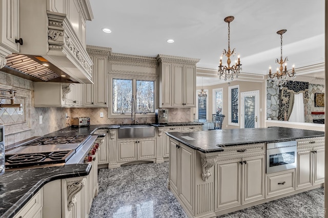 kitchen with built in microwave, sink, pendant lighting, cream cabinetry, and a kitchen island