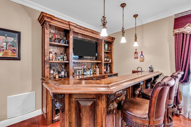 bar with ornamental molding, decorative light fixtures, and hardwood / wood-style flooring